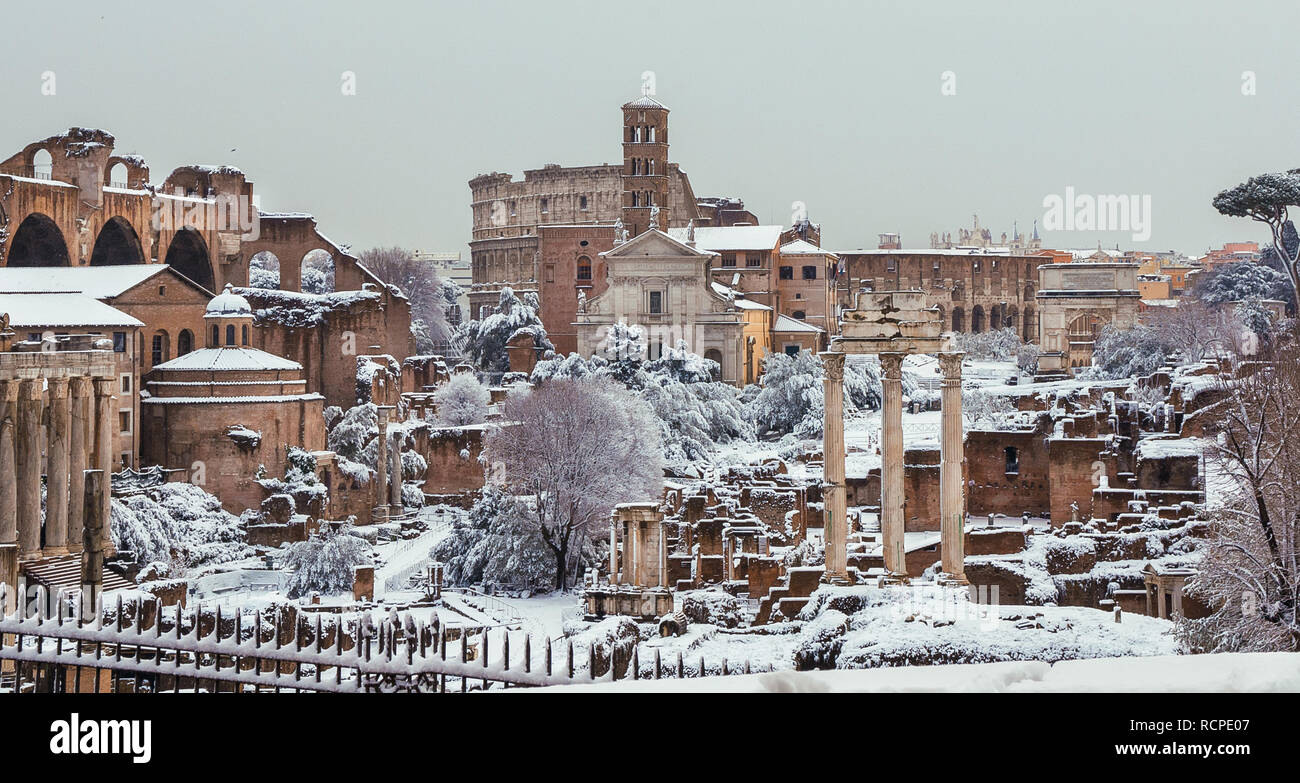 Congelati Roma. Vista del Foro Romano le antiche rovine e il Coliseum coperte da neve Foto Stock