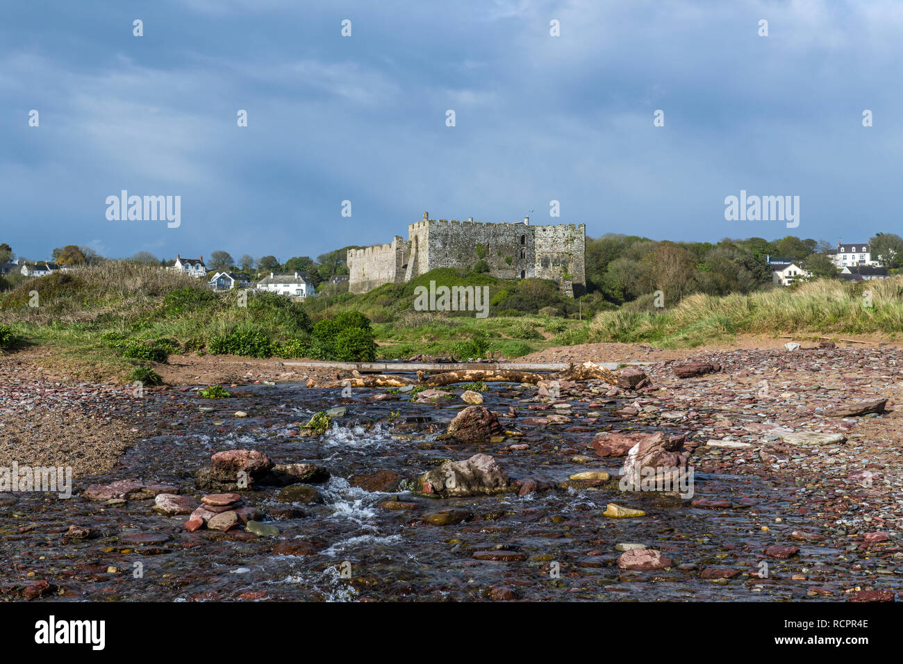 Manorbier Castle e sulla spiaggia di South Pembrokeshire costa nel Galles occidentale con un fiume in primo piano Foto Stock