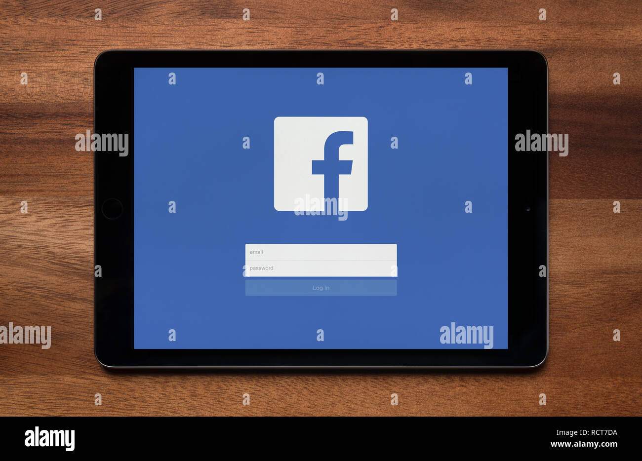 La schermata di accesso di Facebook è visto su un tablet iPad, il quale è appoggiato su un tavolo di legno (solo uso editoriale). Foto Stock