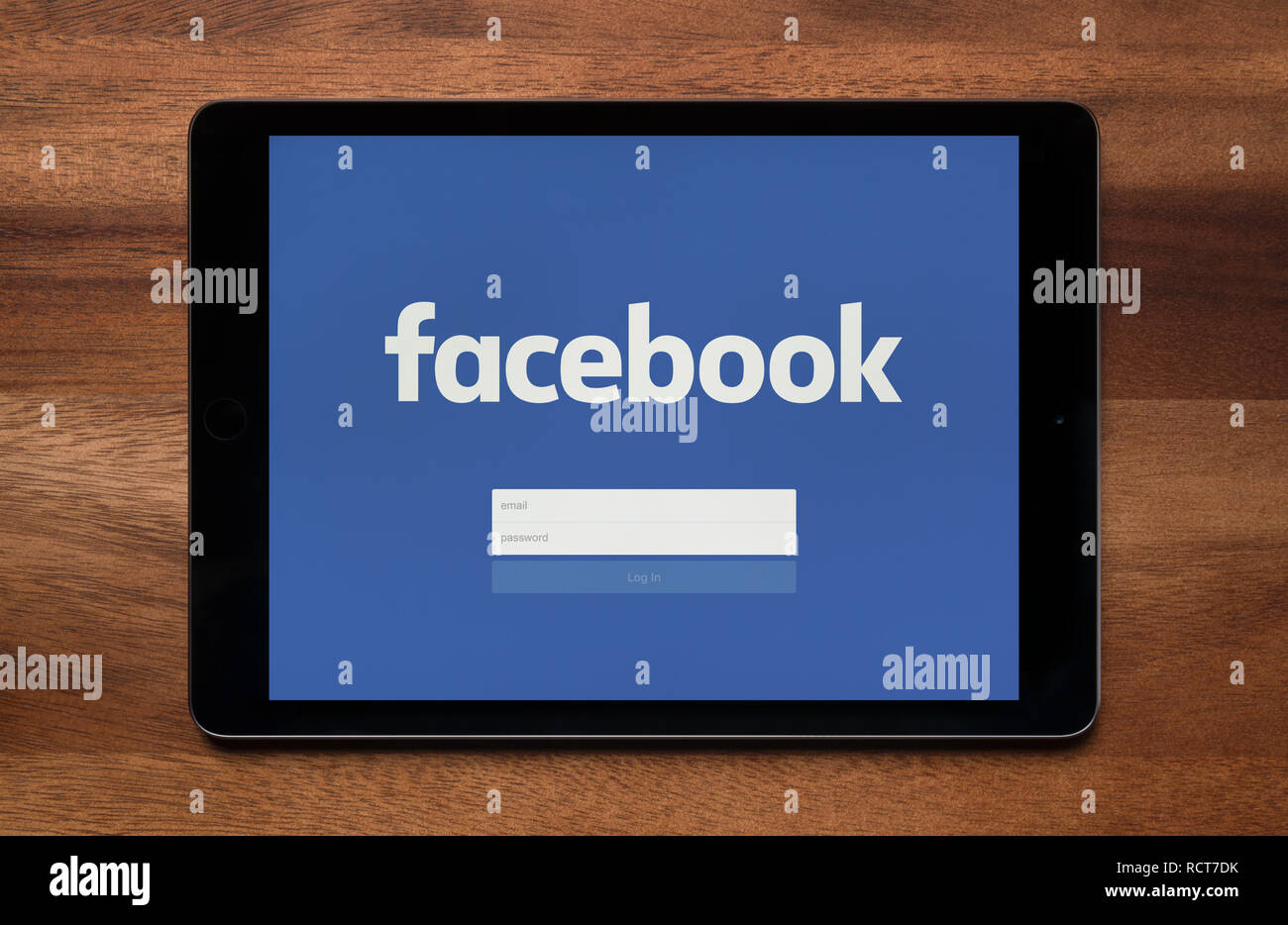 La schermata di accesso di Facebook è visto su un tablet iPad, il quale è appoggiato su un tavolo di legno (solo uso editoriale). Foto Stock