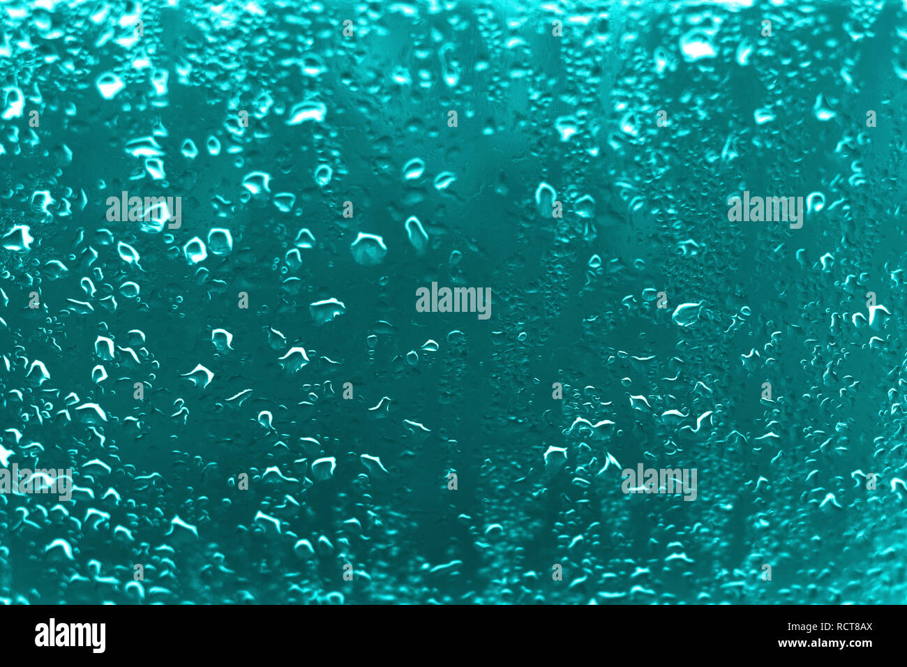 Alto contrasto foto di gocce di pioggia su un vetro di un finestrino con vivaci ciano colore blu Foto Stock