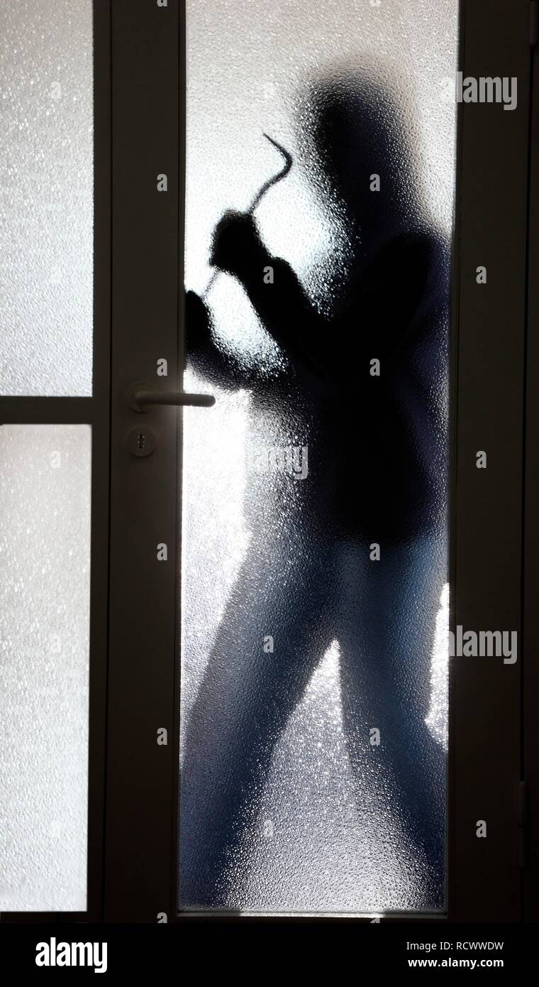 Scasso, ladro su una scala di un palazzo di appartamenti durante il giorno, costringendo oping una porta di vetro Foto Stock
