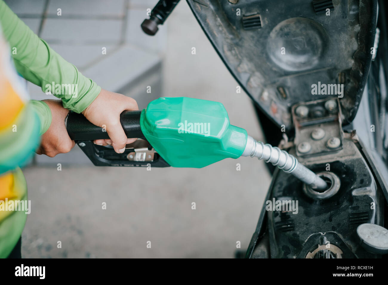 Donna mani di pompaggio del carburante benzina in moto alla stazione di gas. Foto Stock