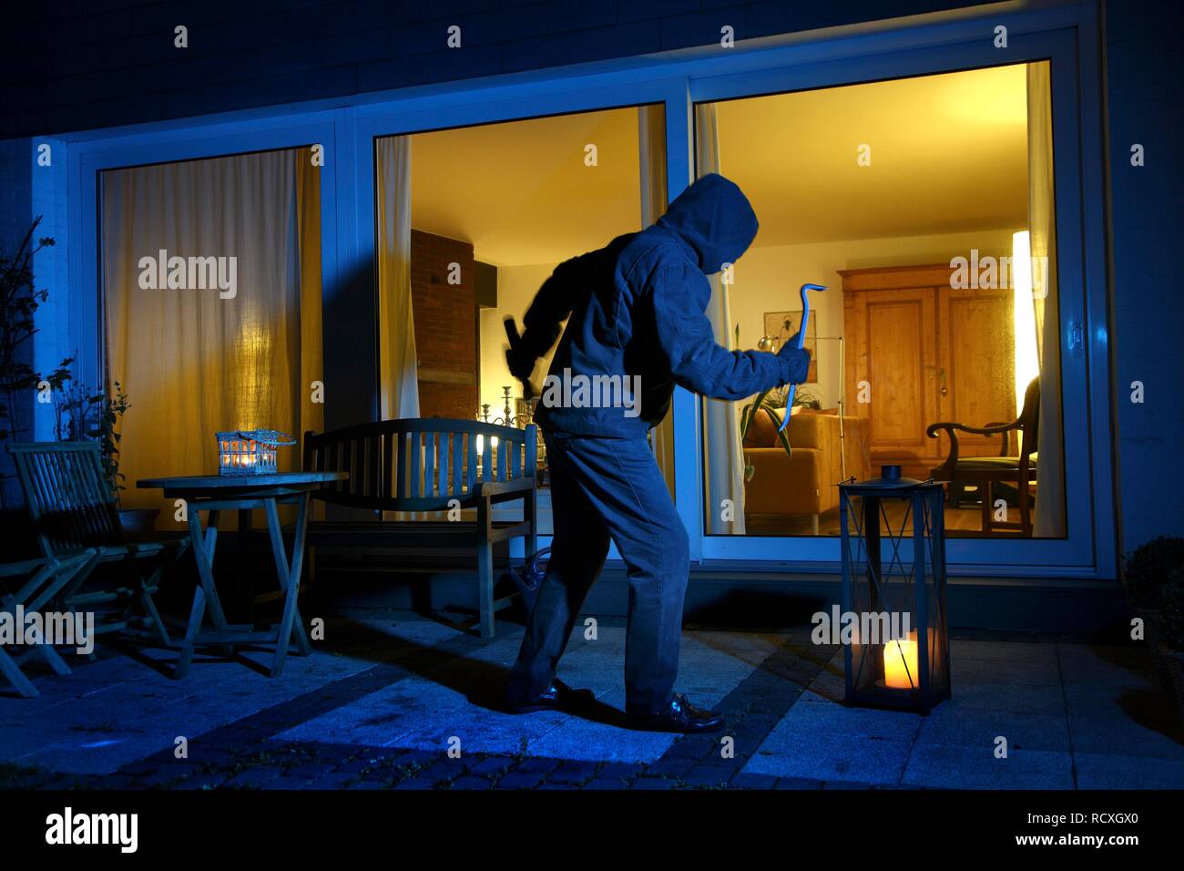 Ladro vuole entrare prepotentemente una casa, si insinua sul terrazzo, immagine simbolica per i furti con scasso nelle abitazioni Foto Stock