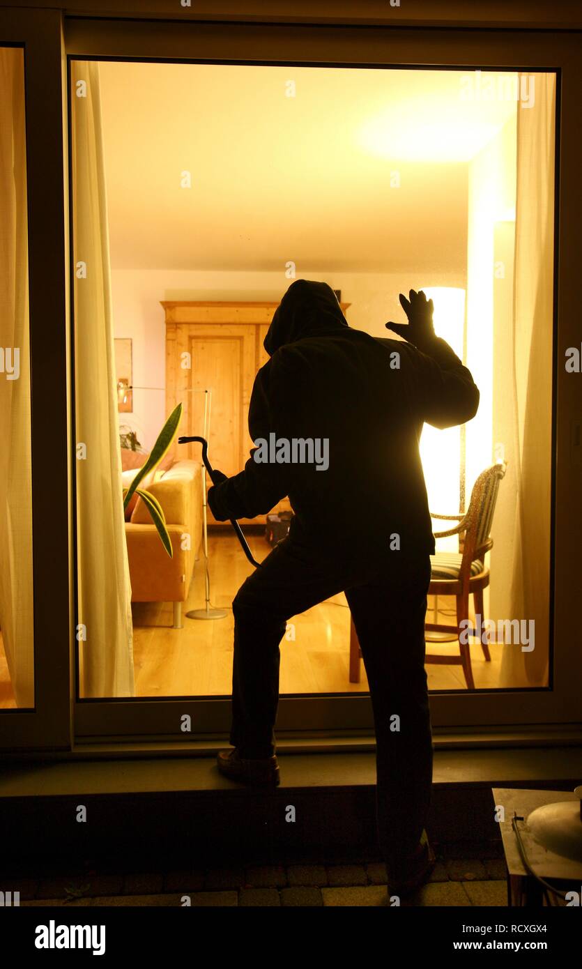 Ladro vuole entrare prepotentemente una casa, si insinua sul terrazzo, immagine simbolica per i furti con scasso nelle abitazioni Foto Stock