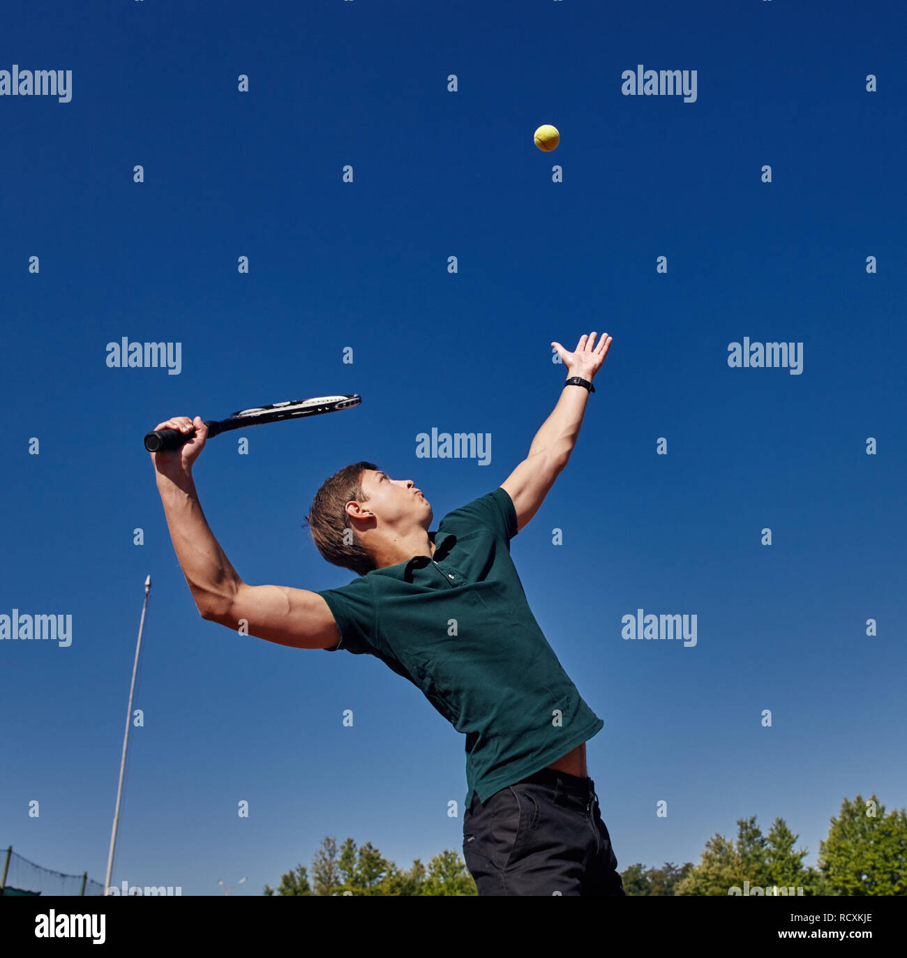 Un uomo giocando a tennis sulla corte su una bella giornata di sole Foto Stock