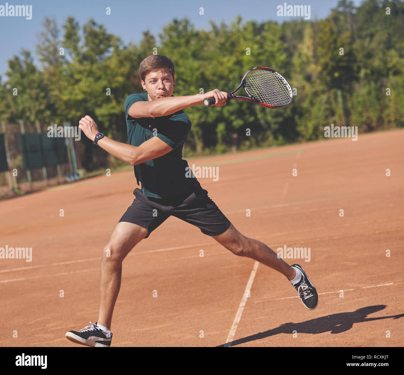 Un uomo giocando a tennis sulla corte su una bella giornata di sole Foto Stock