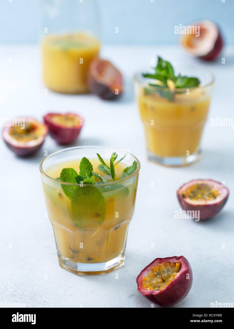 Succo tropicale con frutto della passione, menta in un bicchiere, frutto della passione su uno sfondo blu Foto Stock