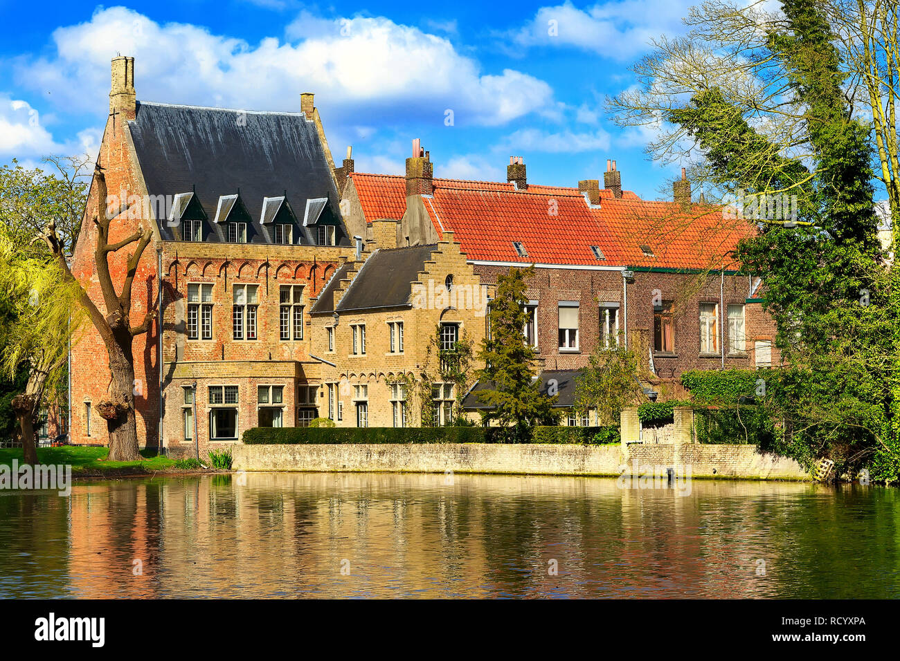 Vista iconico in Bruges, Belgio a Minnewater lago, case medievali contro il cielo blu Foto Stock