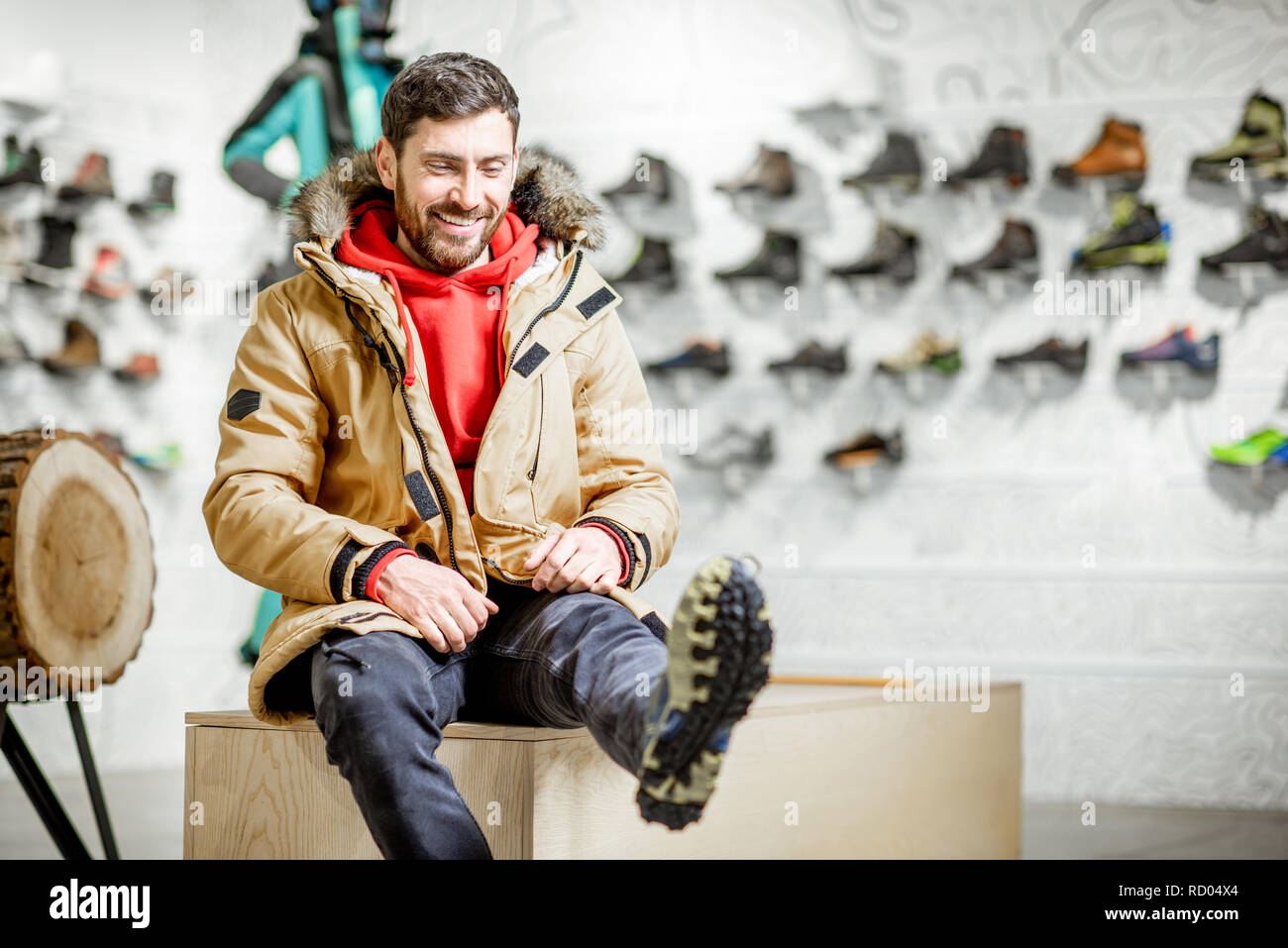 Uomo in giacca invernale cercando scarpe da trekking in montagna seduti  nella sala di montaggio dei moderni sport shop Foto stock - Alamy