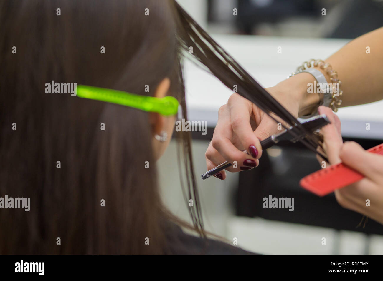 Il parrucchiere fa un taglio di capelli di una donna, una bruna in un salone di bellezza. Foto Stock