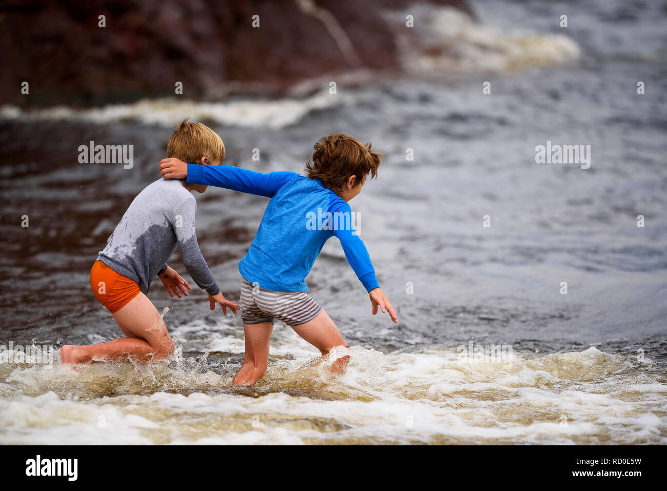 Due ragazzi in piedi ginocchio profondo nel mare avendo divertimento, Stati Uniti Foto Stock