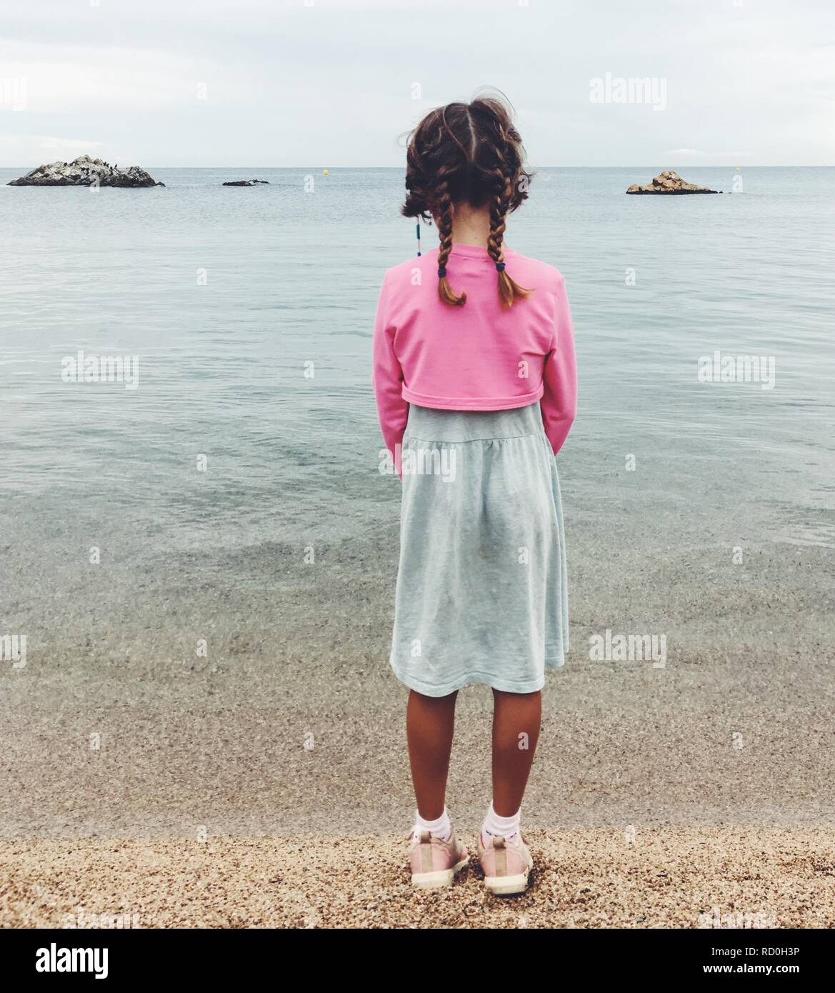 Vista posteriore di una ragazza in piedi su una spiaggia a bordo dell'acqua, Spagna Foto Stock