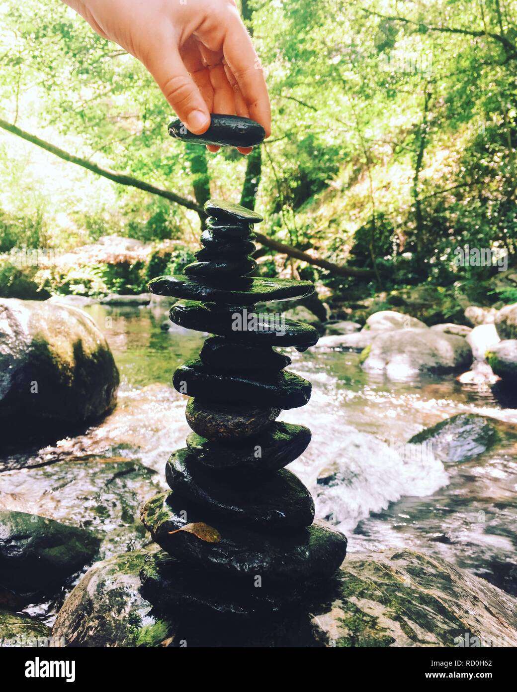 La donna la sovrapposizione di un mucchio di pietre sulla parte superiore di ogni altro da un fiume, Spagna Foto Stock