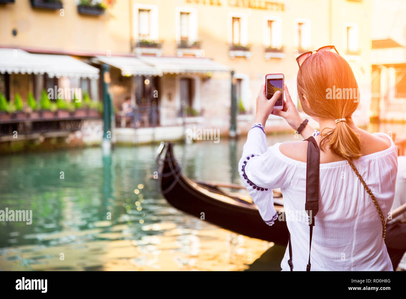 Donna in piedi da un canale di scattare una foto con il suo telefono cellulare, Venezia, Veneto, Italia Foto Stock