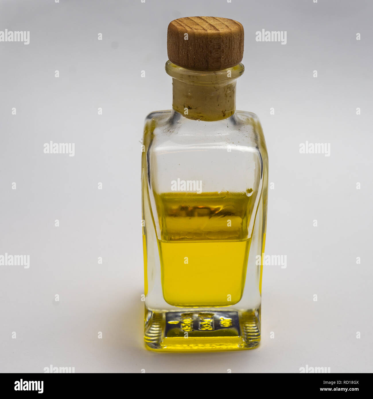 Rettangolare trasparente bottiglia di vetro con un tappo di sughero. Mezzo riempito con un luminoso giallo liquido, esposte contro uno sfondo bianco. Foto Stock
