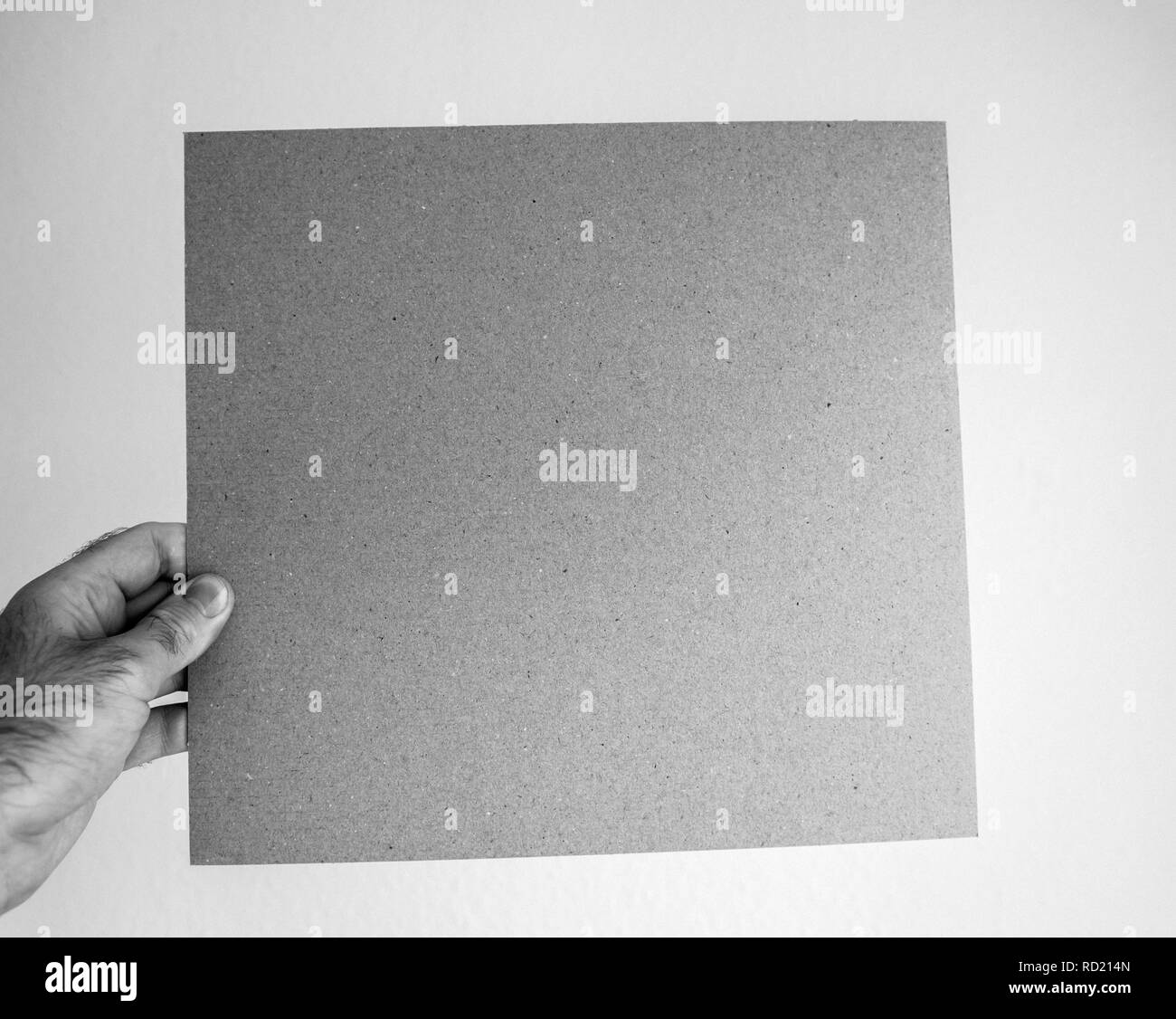 Uomo con cartone grigio pagina contro lo sfondo grigio - immagine in bianco e nero Foto Stock