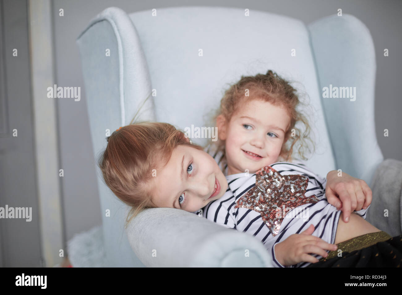 Due piccole sorelle in pigiama seduto in una sedia Foto Stock