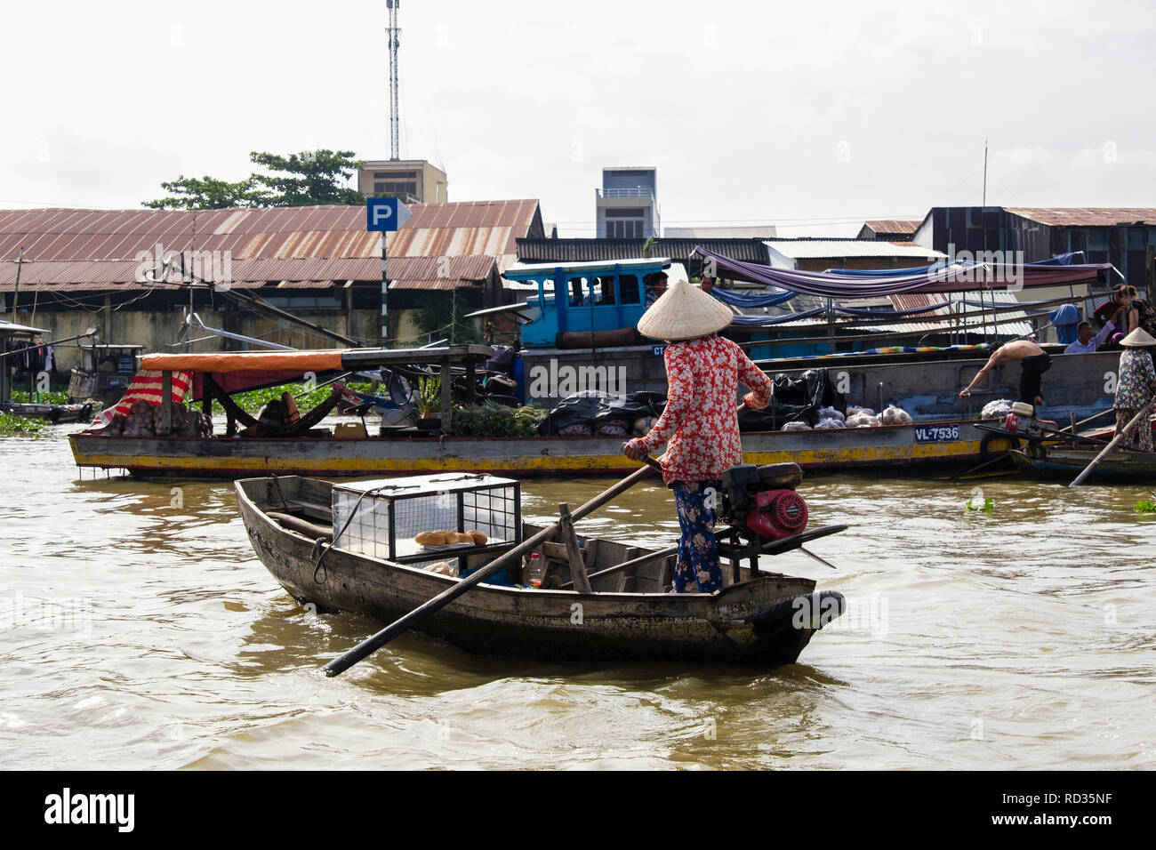 Donna vendita di pani da una piccola barca tradizionale nel mercato galleggiante sul Fiume Hau. Can Tho, Delta del Mekong, Vietnam Asia Foto Stock