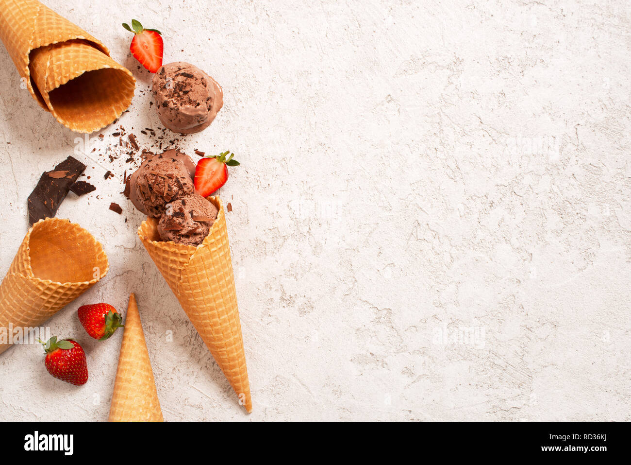 Sfondo con palline di gelato al cioccolato con fragola nel cono di cialda, spazio di copia Foto Stock