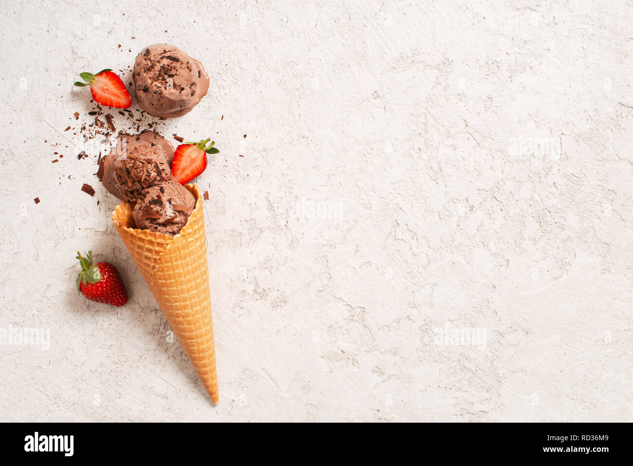 Sfondo con palline di gelato al cioccolato con fragola nel cono di cialda, spazio di copia Foto Stock