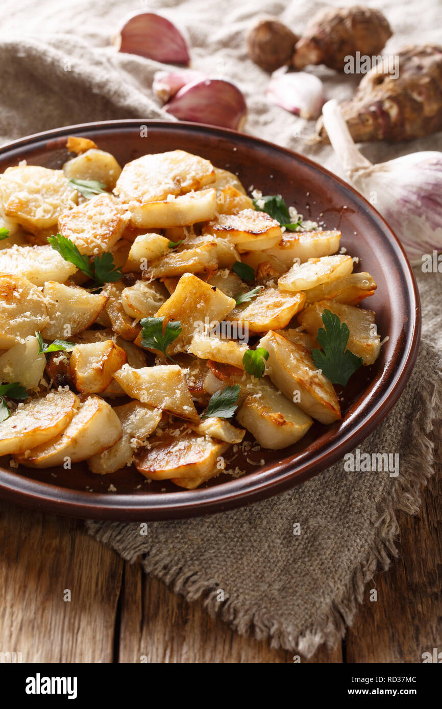Gerusalemme i carciofi arrosto con aglio, il formaggio e il prezzemolo closeup su una piastra sul piano verticale. Foto Stock