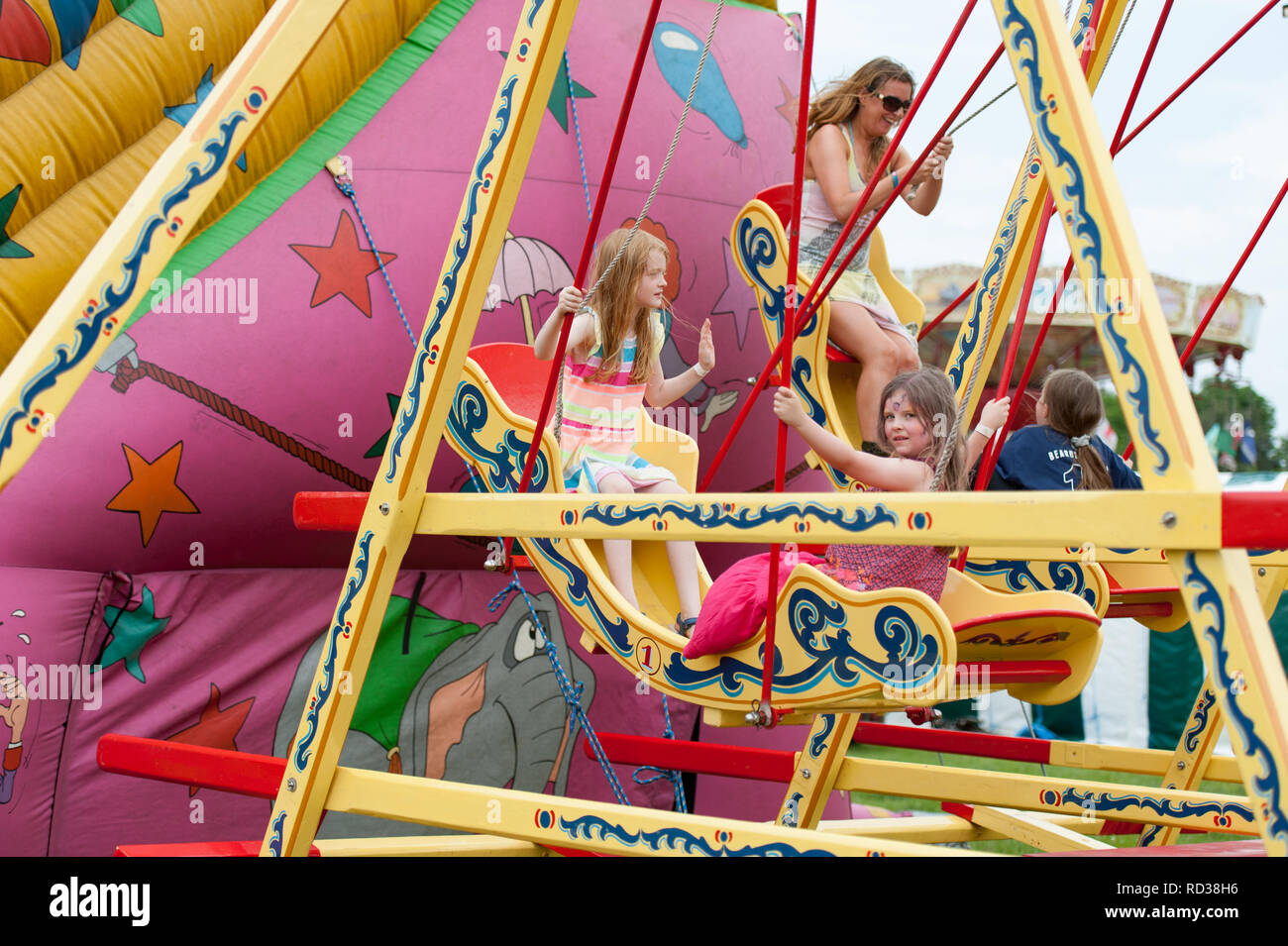 Bambini godendo le barche di rotazione in corrispondenza di un festival di musica Foto Stock