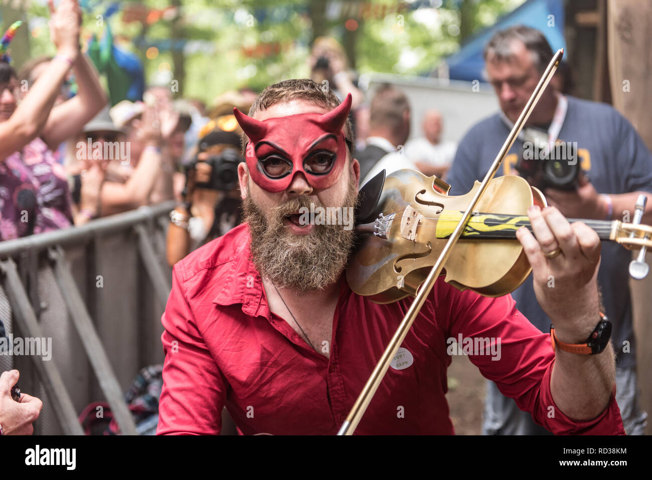 Uomo vestito come il diavolo a suonare il violino a un festival di musica Foto Stock