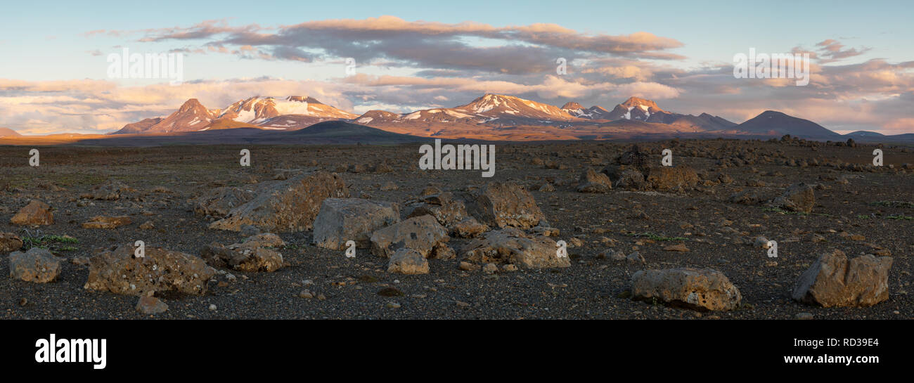 Panorama di una grande pietra scura del paesaggio in background con una gamma di montagna incandescente nella luce della sera - Location: Islanda, altopiani, Kerlingar Foto Stock