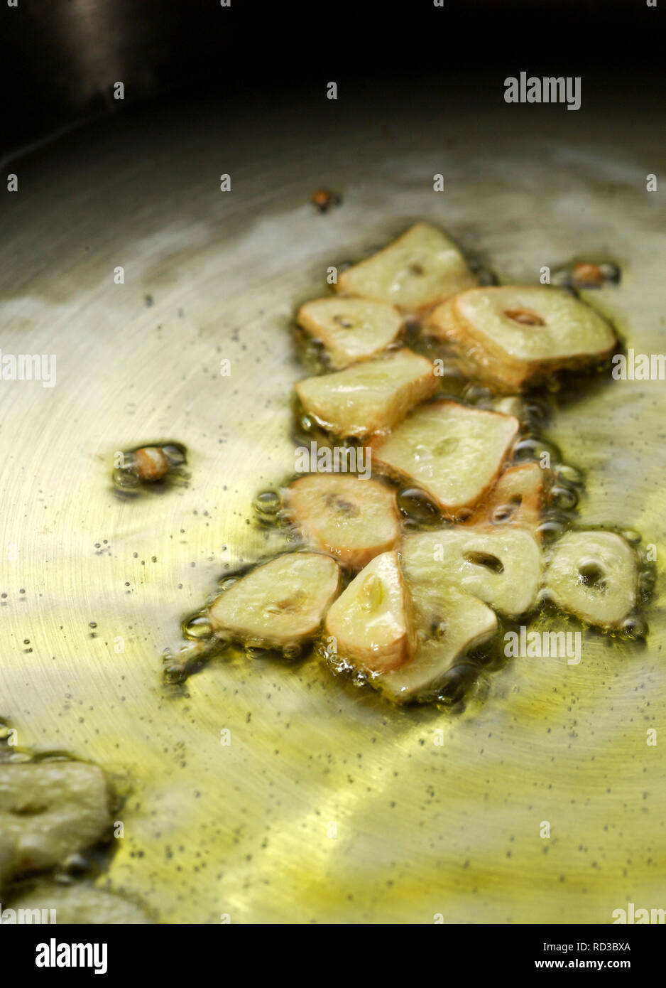 Close up di fettine di aglio la frittura in olio bollente, studio shot Foto Stock