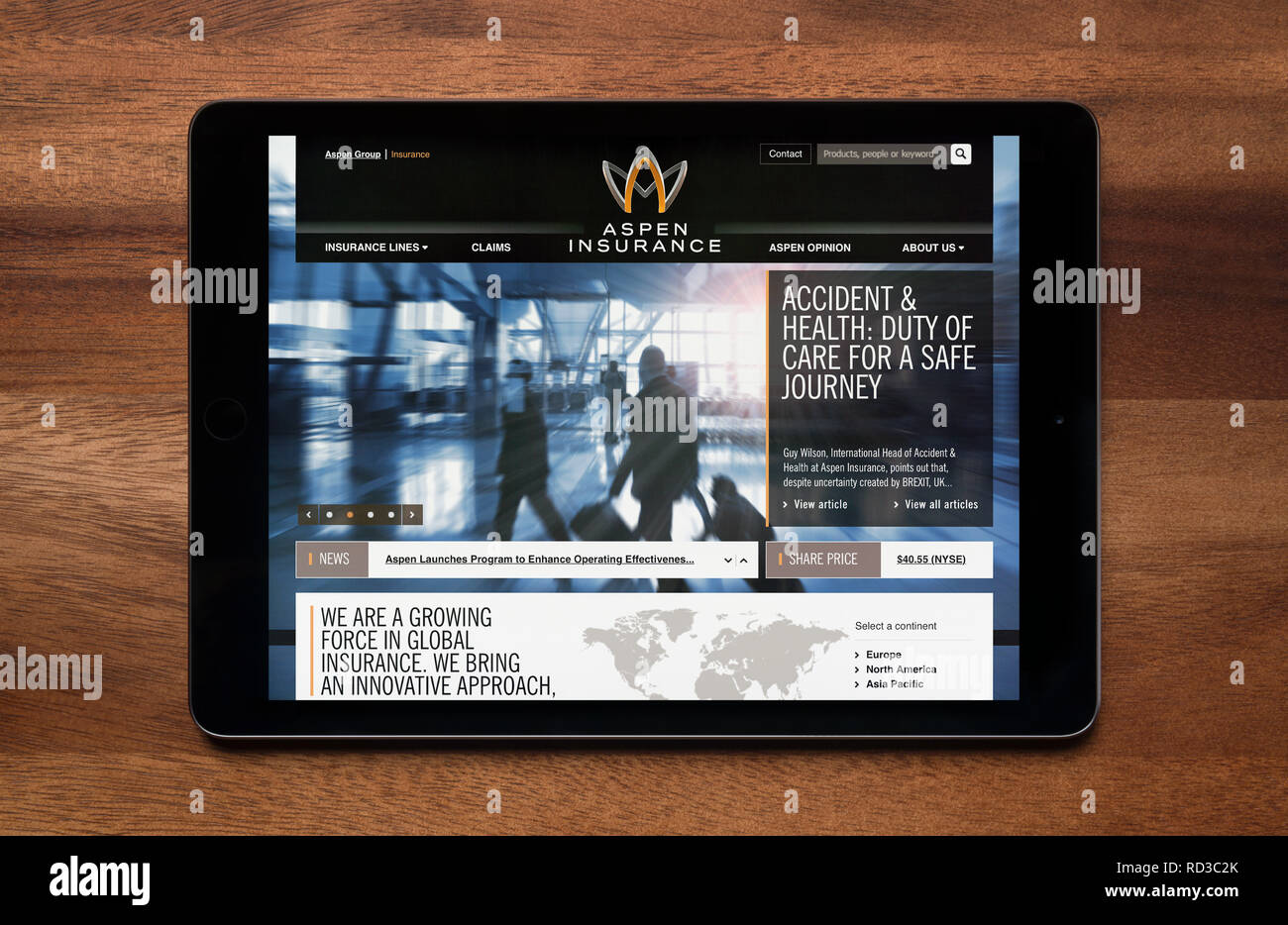 Il sito web di Aspen assicurazione è visto su un tablet iPad, il quale è appoggiato su un tavolo di legno (solo uso editoriale). Foto Stock