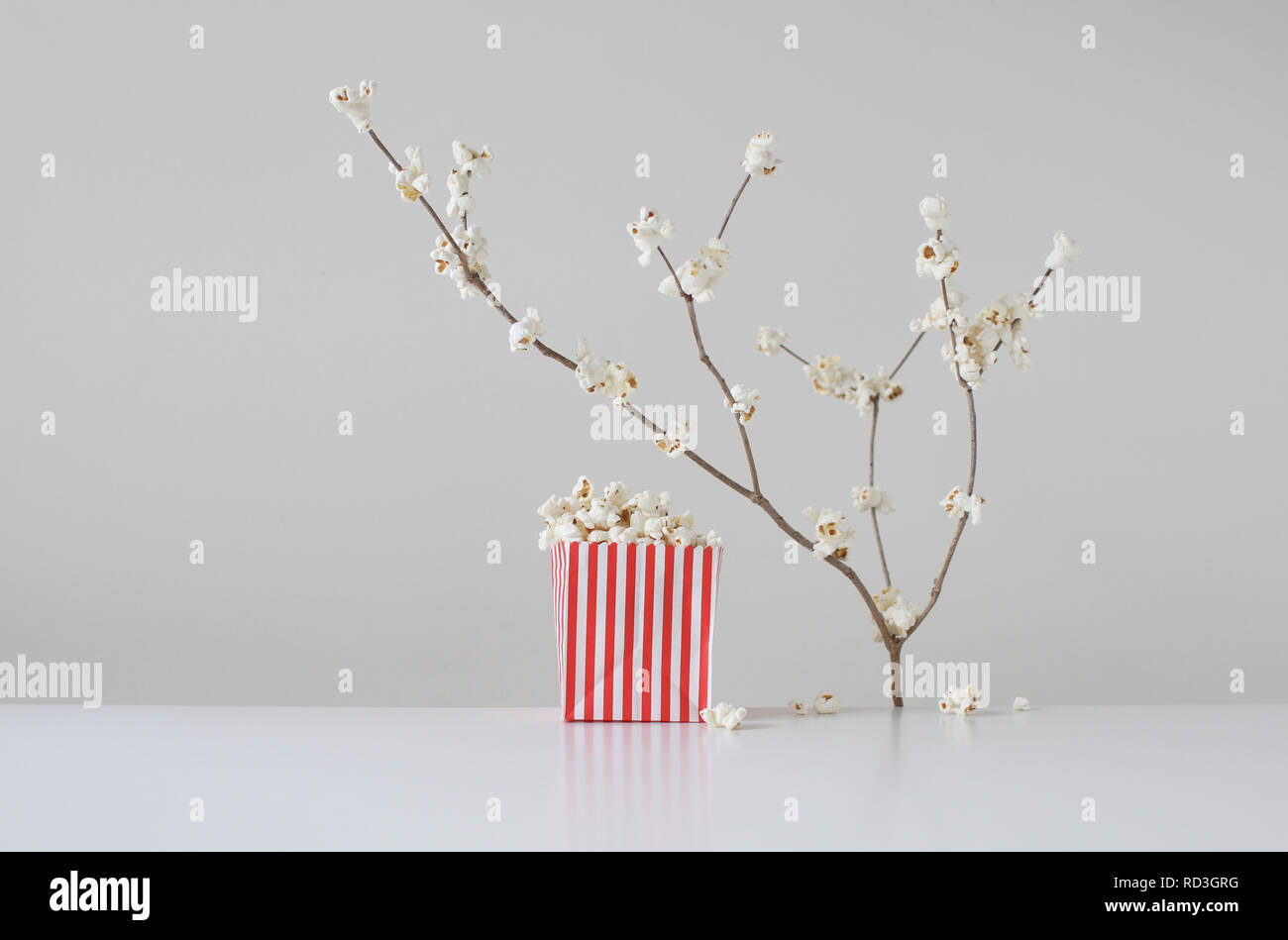 Fiori di ciliegio concettuali che crescono su un albero accanto a un sacchetto di popcorn Foto Stock