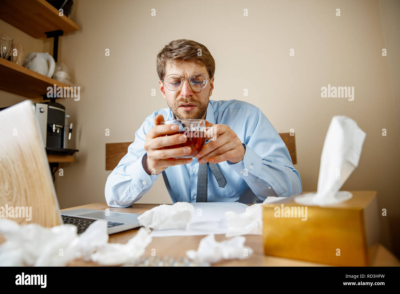 La sensazione di malessere e stanco. L'uomo con la tazza di tè caldo lavorando in ufficio, imprenditore catturati freddo, l'influenza stagionale. Pandemia di influenza, la prevenzione delle malattie, aria condizionata in office malattia di causa Foto Stock