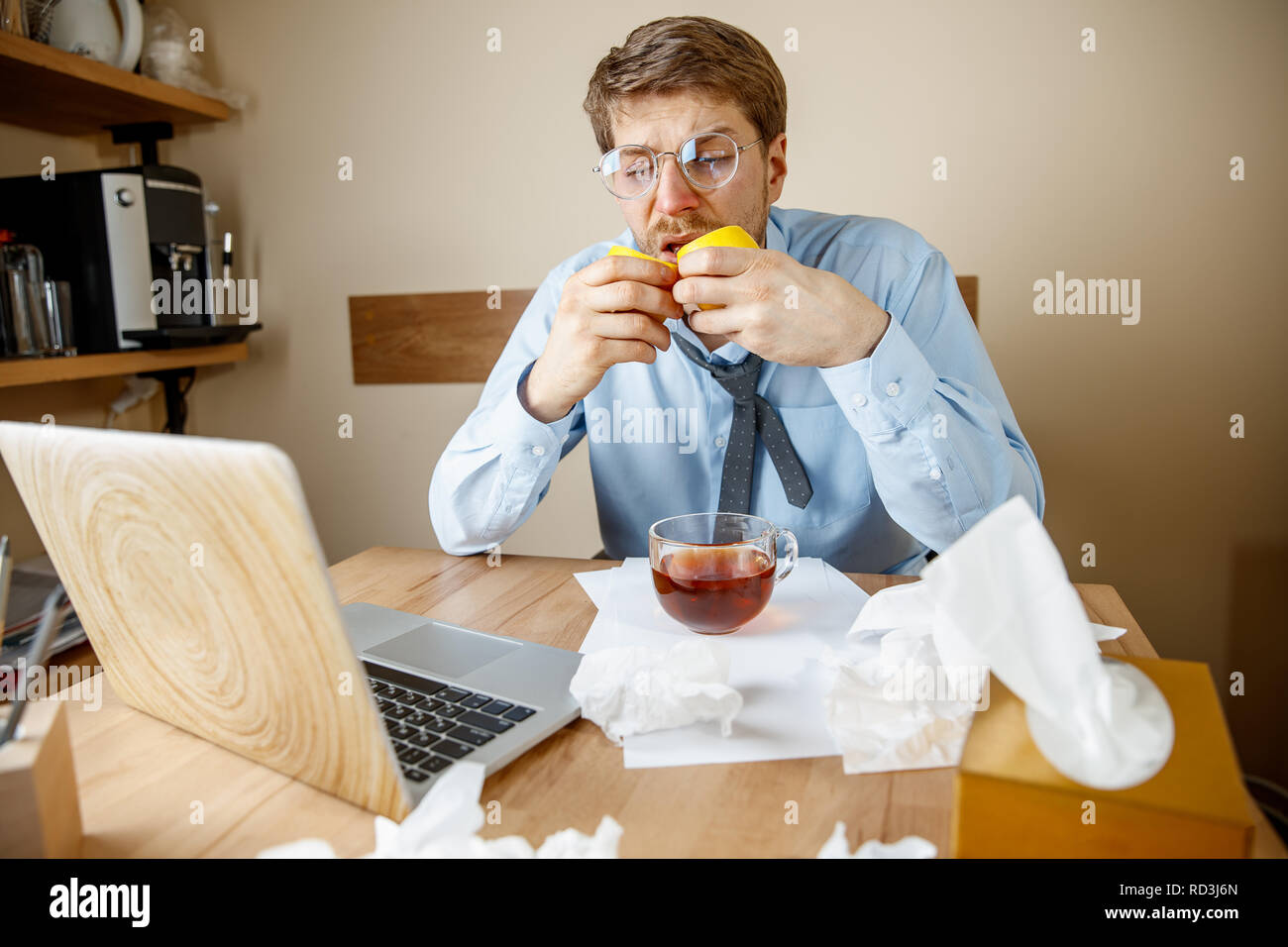 La sensazione di malessere e stanco. L'uomo con il limone e la tazza di tè caldo lavorando in ufficio, imprenditore catturati freddo, l'influenza stagionale. Pandemia di influenza, la prevenzione delle malattie, aria condizionata in office malattia di causa Foto Stock