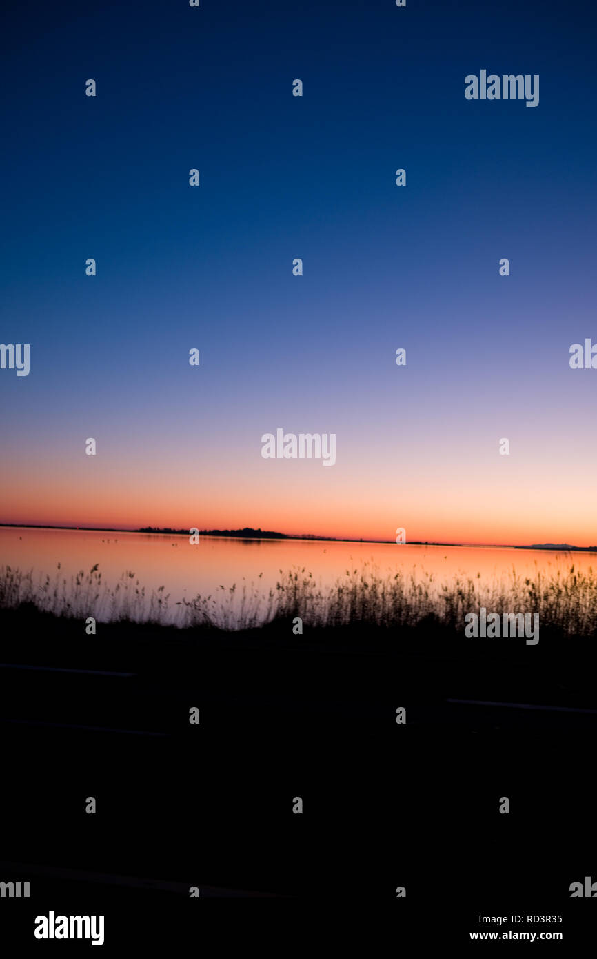 Acqua delicato ance si stagliano contro un lago durante un tramonto mozzafiato che quasi assomiglia ad un acquerello nel Languedoc Roussillon, Francia Foto Stock