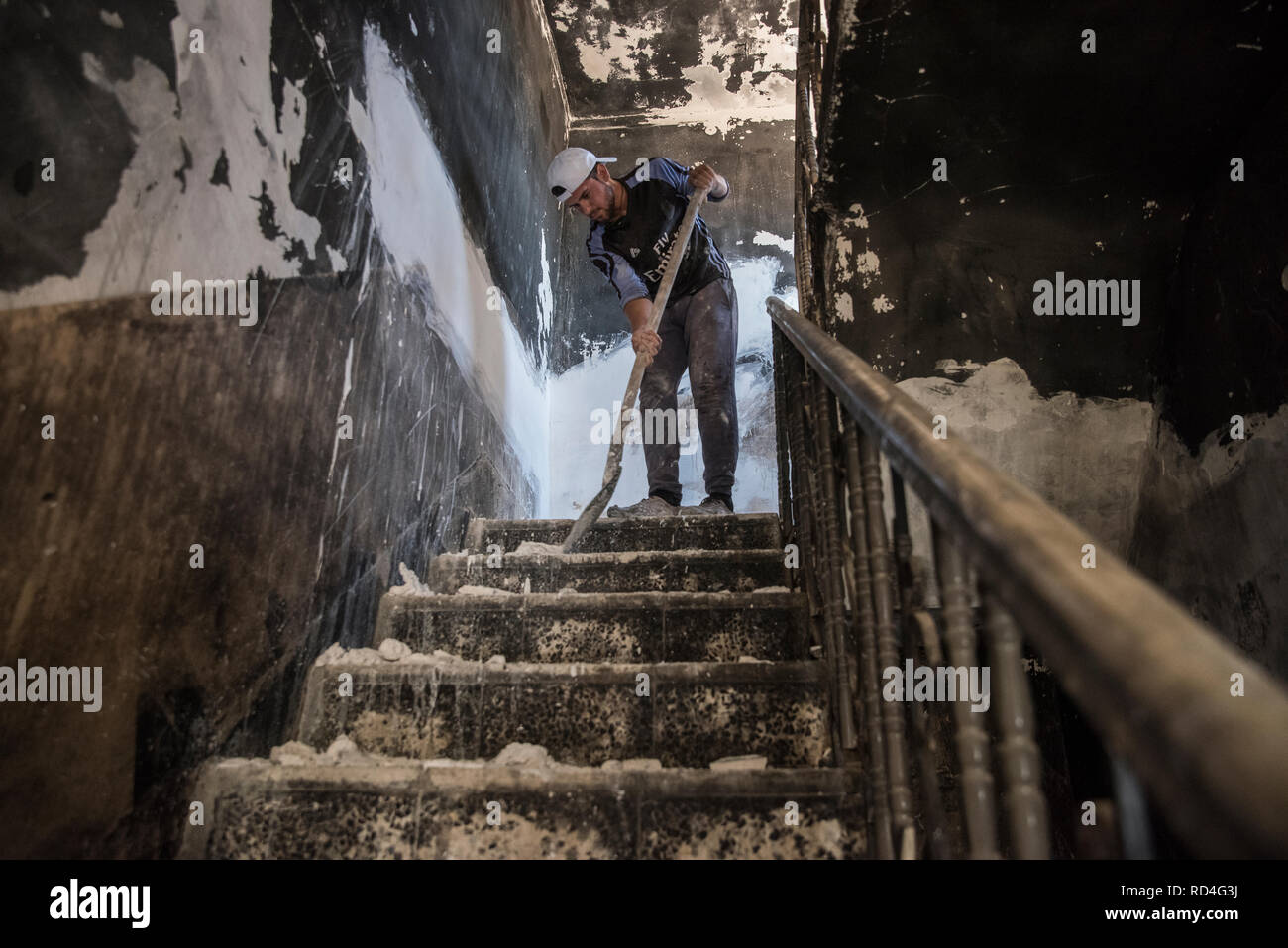 Un ragazzo vede la pulizia dei detriti all'interno di una famiglia. Molte di queste case sono ancora contaminato con residui bellici esplosivi. In agosto 2014, lo Stato islamico catturato Sinjar, la città principale della popolazione Yazidi in Iraq. Ora, con la città in rovine e Nazioni Unite in Iraq e UN-Habitat hanno iniziato un recupero urbanistico programma in gran parte finanziato dal governo della Repubblica federale di Germania. Questo programma impiega la gente della regione per ricostruire la maggior parte delle famiglie danneggiate. Foto Stock
