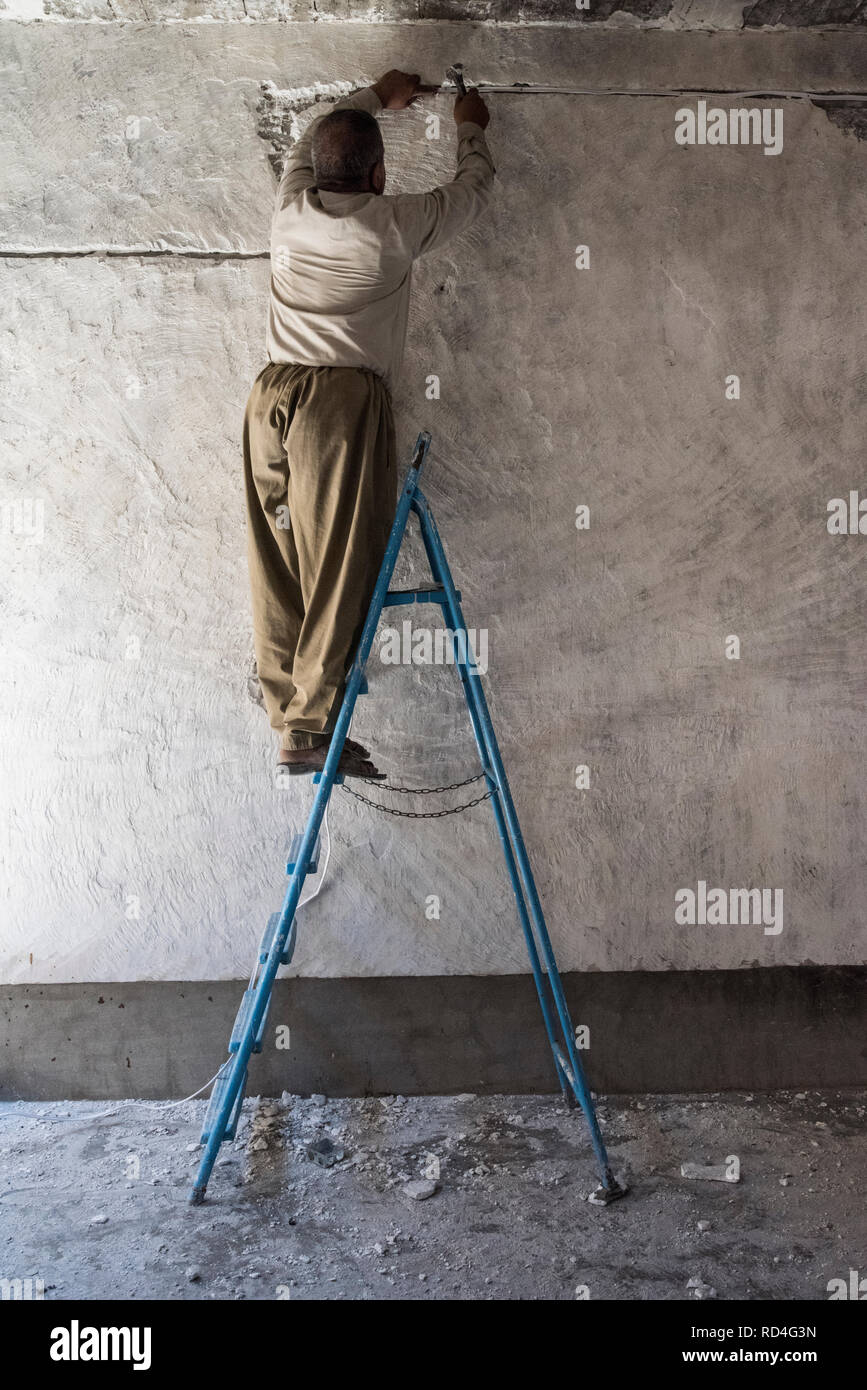 Un uomo visto che partecipano al lavoro di ricostruzione a Sinjar (Iraq), un progetto finanziato dal governo della Repubblica federale di Germania e le Nazioni Unite. In agosto 2014, lo Stato islamico catturato Sinjar, la città principale della popolazione Yazidi in Iraq. Ora, con la città in rovine e Nazioni Unite in Iraq e UN-Habitat hanno iniziato un recupero urbanistico programma in gran parte finanziato dal governo della Repubblica federale di Germania. Questo programma impiega la gente della regione per ricostruire la maggior parte delle famiglie danneggiate. Foto Stock
