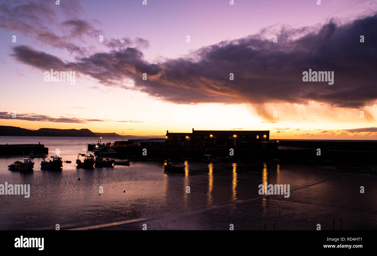 Lyme Regis, Dorset, Regno Unito.Il 17 gennaio 2019. Regno Unito: Meteo il cielo si illumina con golden sunrise di colori a Cobb come Lyme Regis si risveglia in un luminoso e freddi inverni di mattina. Credito: Celia McMahon/Alamy Live News Foto Stock