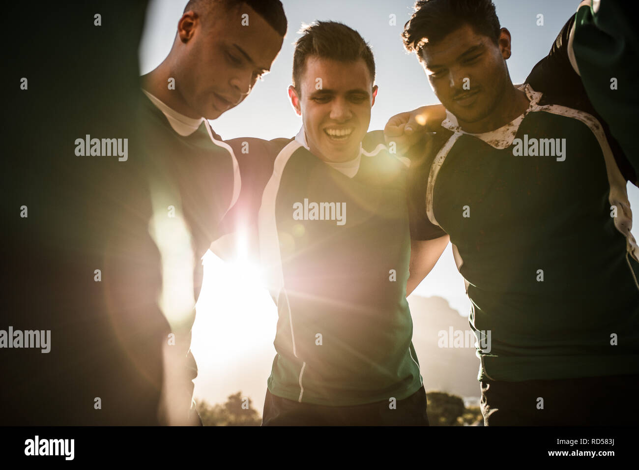 Squadra di giocatori di rugby in piedi in un huddle sulla luminosa giornata di sole. Gruppo di sportivi in piedi in cerchio dopo la partita. Foto Stock