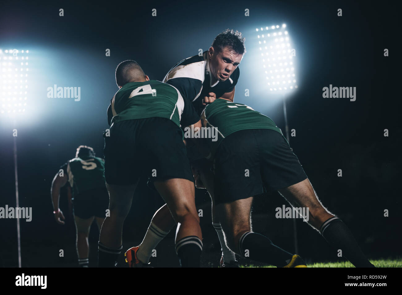 giocatori di rugby che lottano per la palla durante la partita notturna. il giocatore di rugby ha affrontato i giocatori della squadra avversaria in una partita. Foto Stock