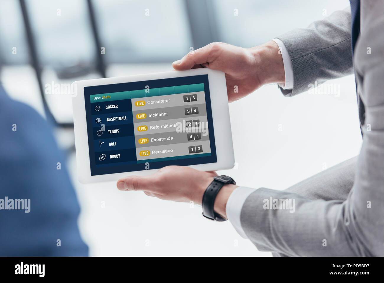Vista parziale di imprenditore tenendo tavoletta digitale con scommesse sportive app sullo schermo Foto Stock
