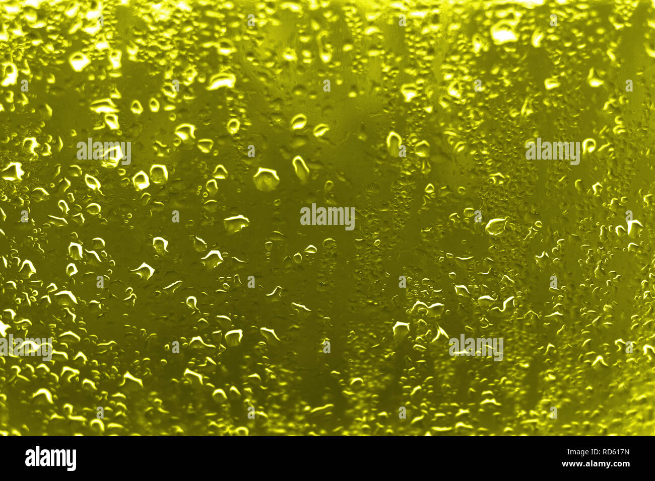 Alto contrasto foto di gocce di pioggia su un vetro di un finestrino con vividi di colore giallo dorato Foto Stock