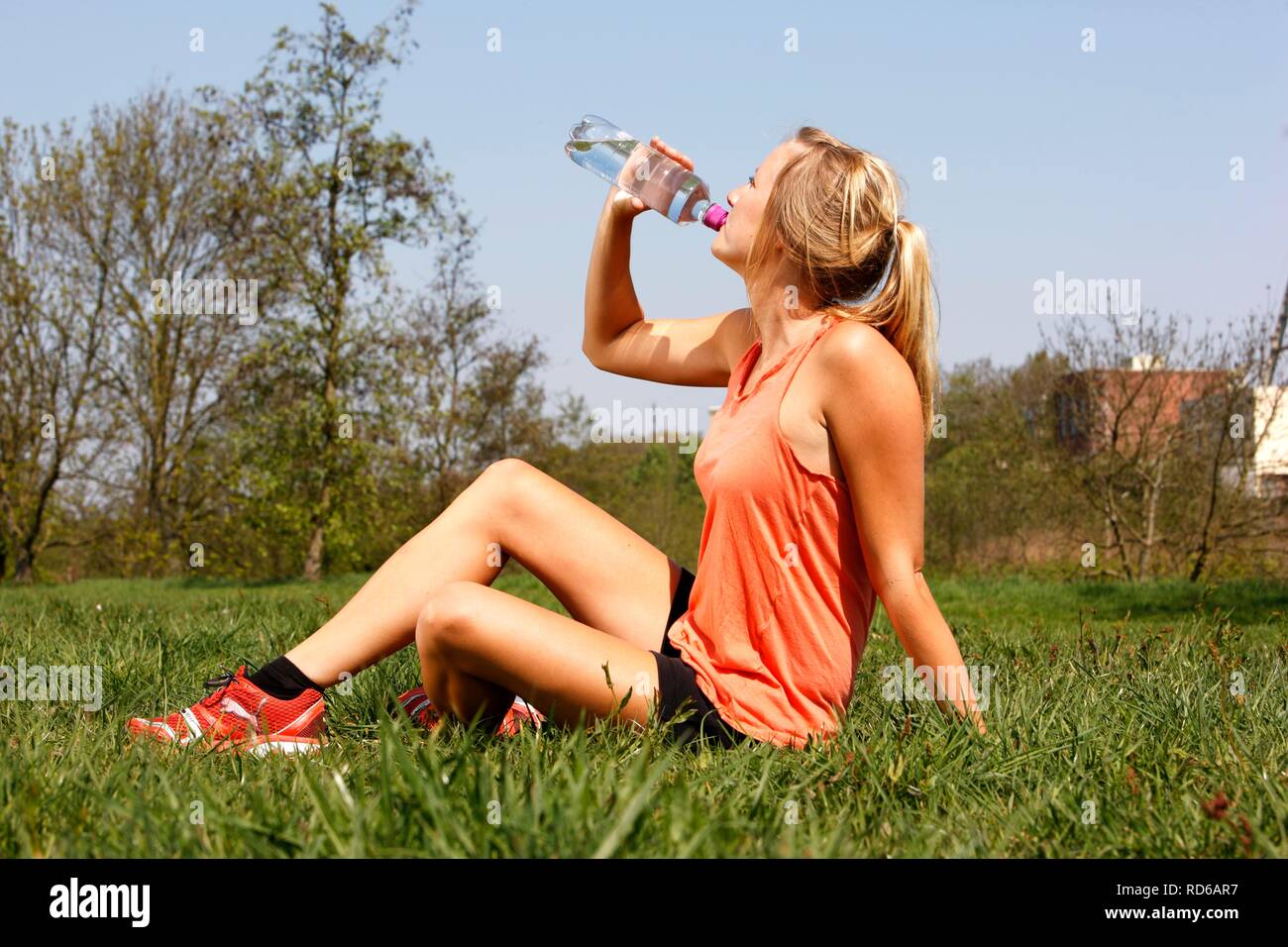 Giovane donna, 25-30 anni, bere da una bottiglia di acqua dopo esercizio Foto Stock