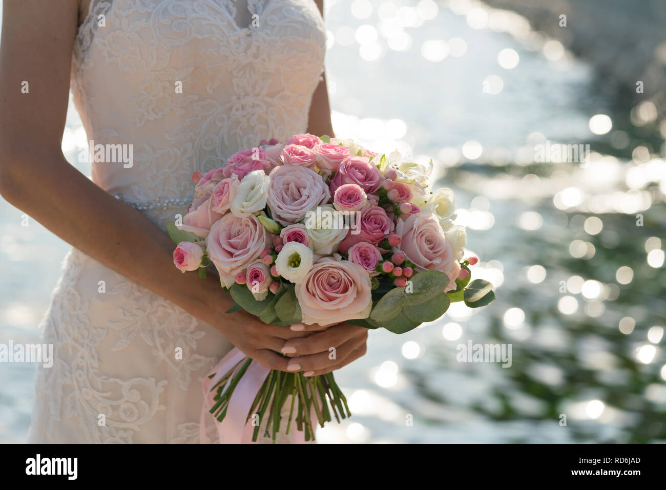 Sposa tiene in mano una rosa e bianco Bouquet nozze sullo sfondo del mare Foto Stock