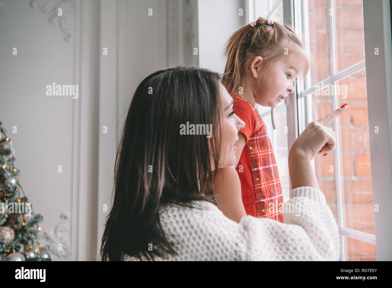 Amorevole Madre a giocare con la sua bambina guardando la finestra Foto Stock