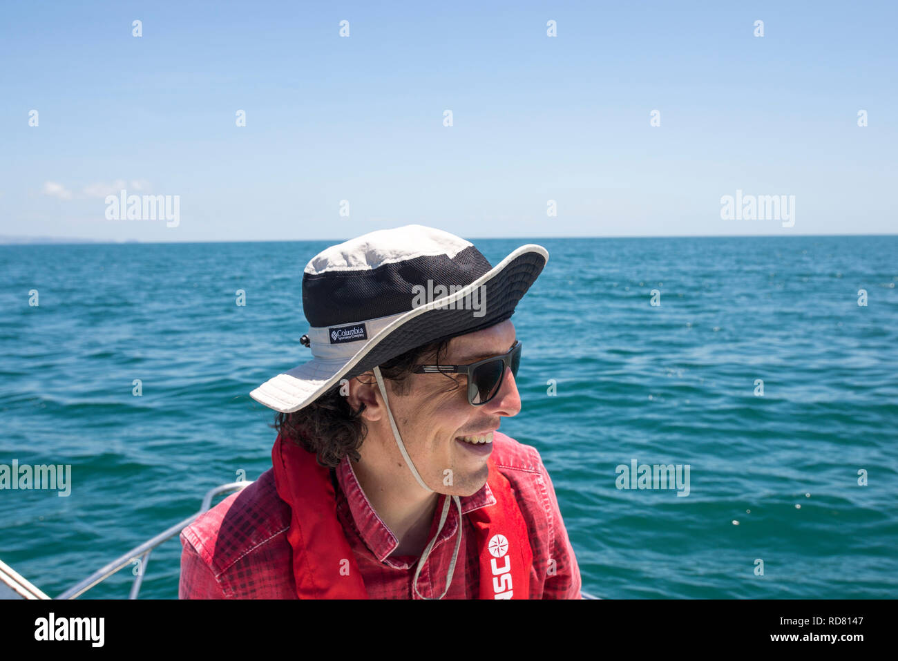 Uomo in hat e sun-glass pesca in barca con giubbotto di salvataggio Foto Stock