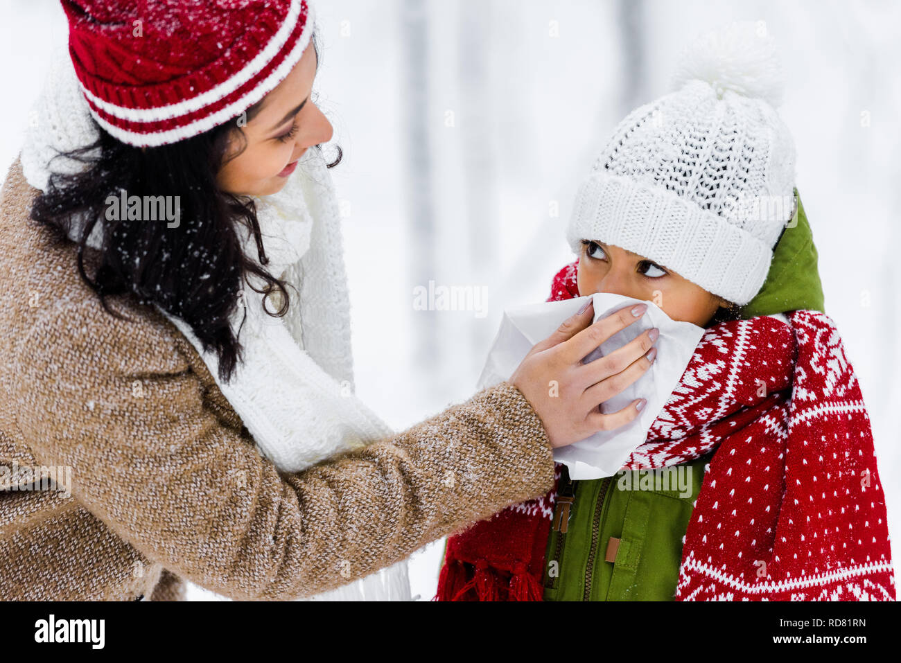 African American donna strofinando con igienico naso di graziosi figlia in winter park Foto Stock