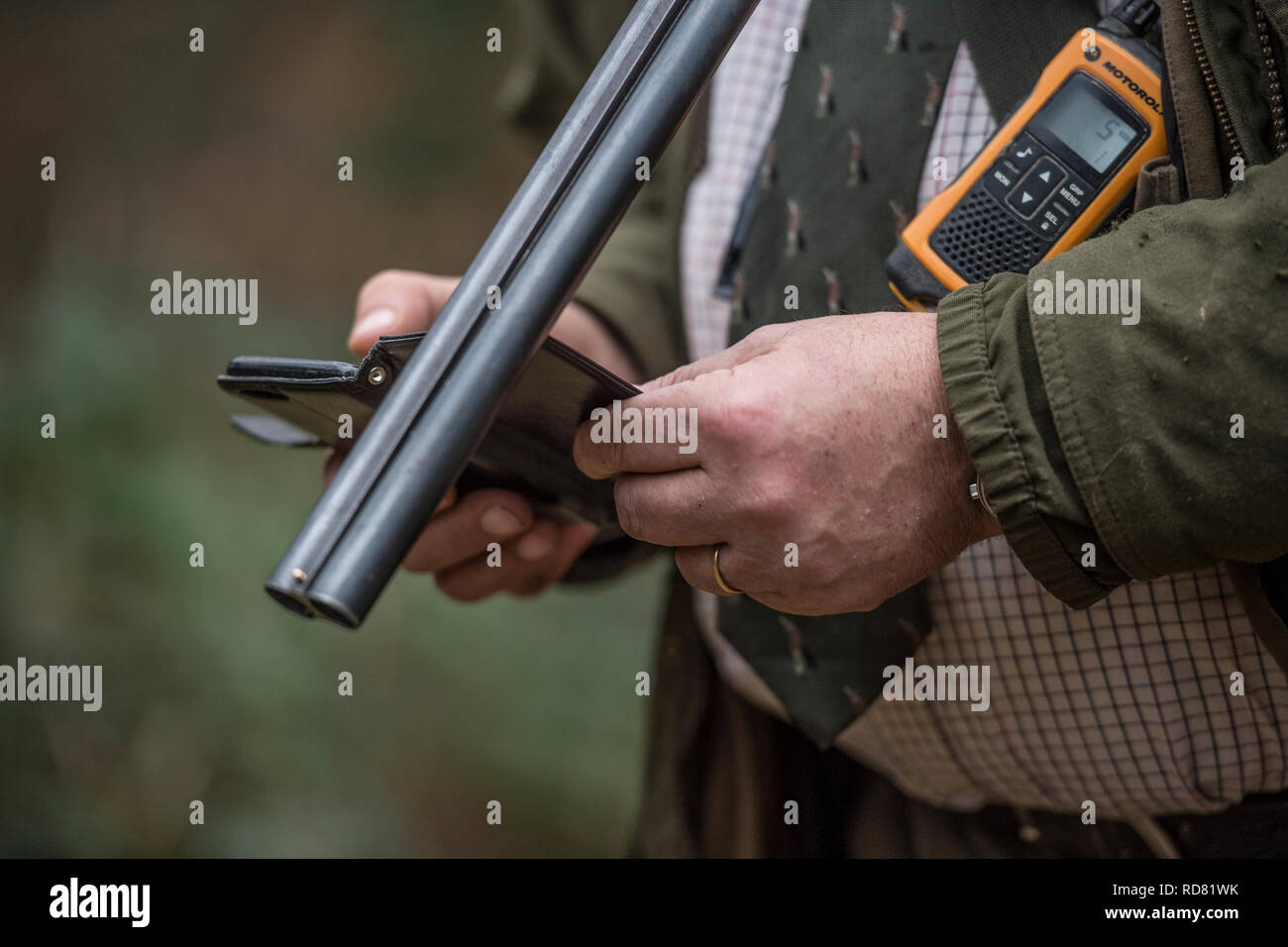 uomo con fucile, radio e telefono cellulare Foto Stock