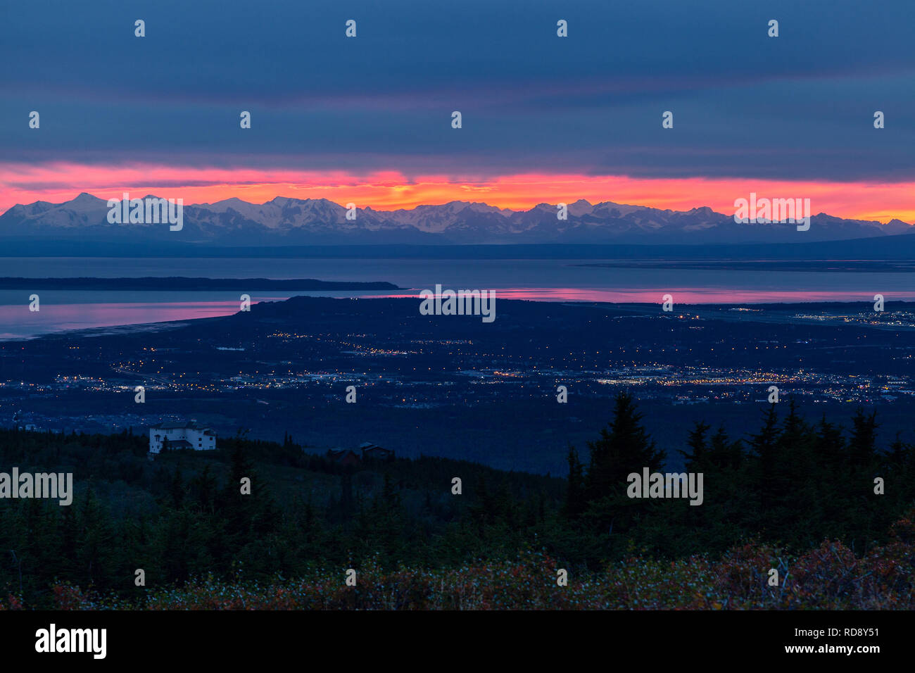 Il sole tramonta dietro le montagne Tordrillo come tenebre cade sopra la città di Anchorage in Alaska, Foto Stock