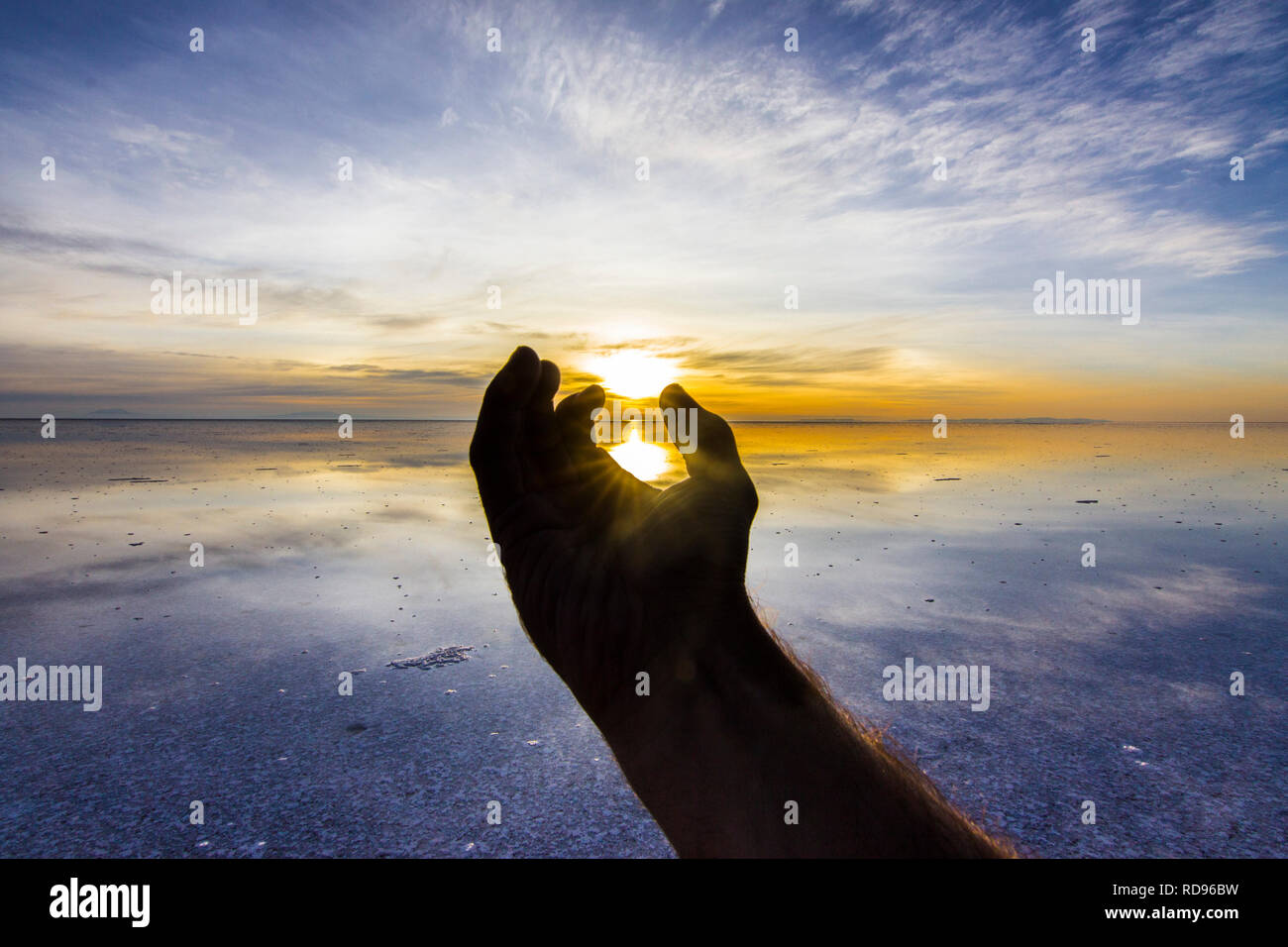 Una mano per la speranza su questo pianeta incredibile Terra. Cercando di prendere il sole presso le saline di Uyuni all'interno di un idilliaco paesaggio colorato con riflessi in acqua Foto Stock